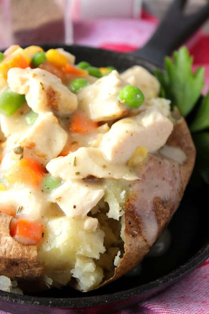 Imagen del primer del pollo y de las verduras en una patata cocida.