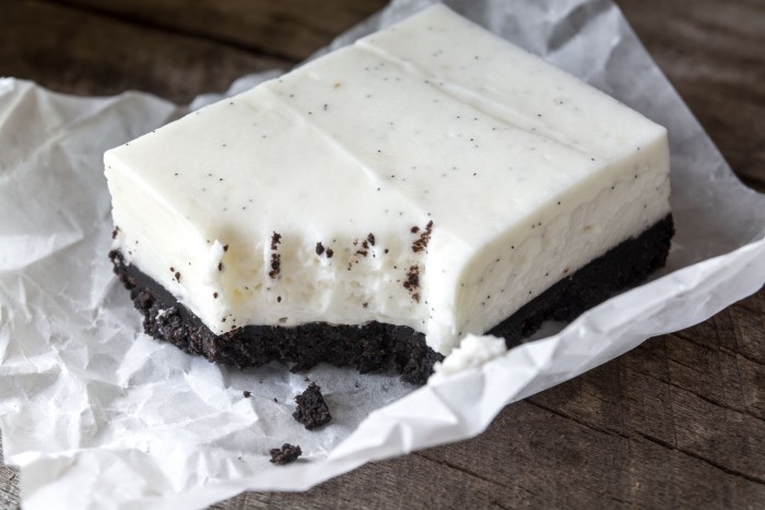 Cuadrados de pastel de queso con frijoles de vainilla sin hornear con una profunda corteza de galleta de chocolate oscuro