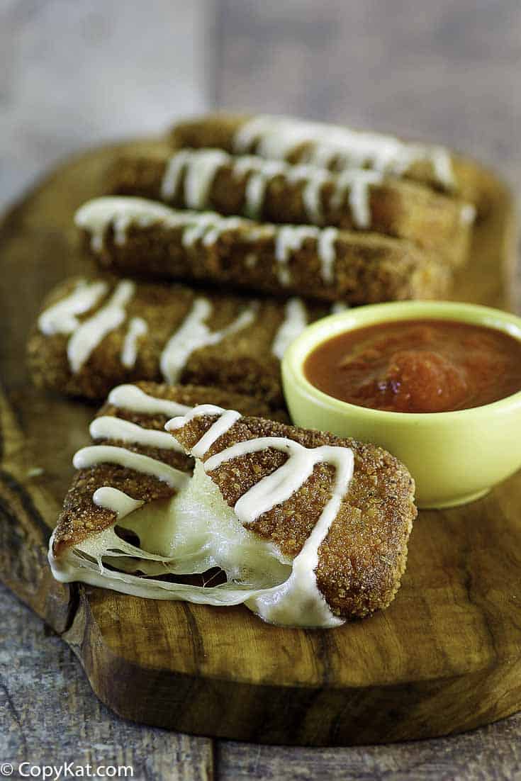Tri&aacute;ngulos de queso mozzarella fritos caseros Olive Garden y salsa marinara en un plato.