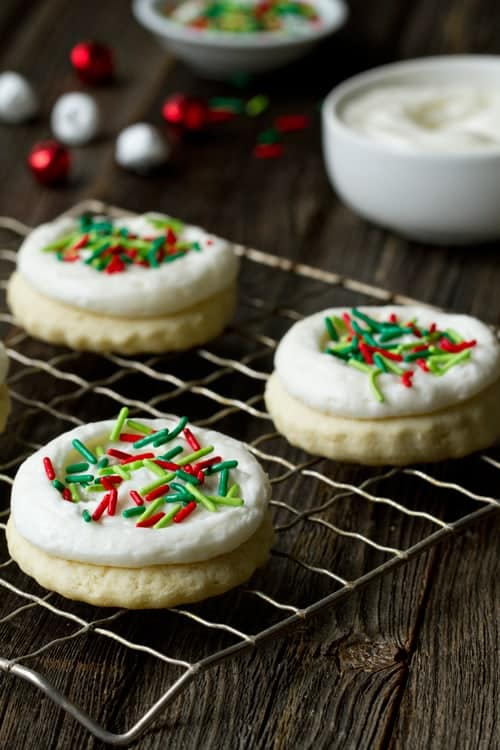Sweet Sour Cream Cut Out Cookies are a festive addition to any holiday cookie tray. Soft and shiny frosting with festive sprinkles makes them beautiful.
