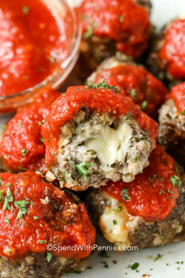 Cerca de una mozzarella rellenas de alb&oacute;ndigas con salsa de tomate casera en la parte superior. Le sacan una mordida.