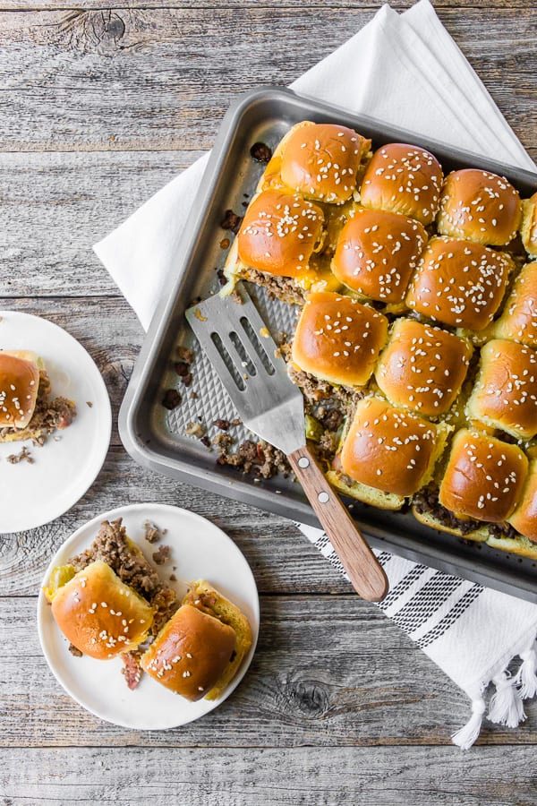 deslizadores de hamburguesa con queso y tocino horneado en una sartén y placa
