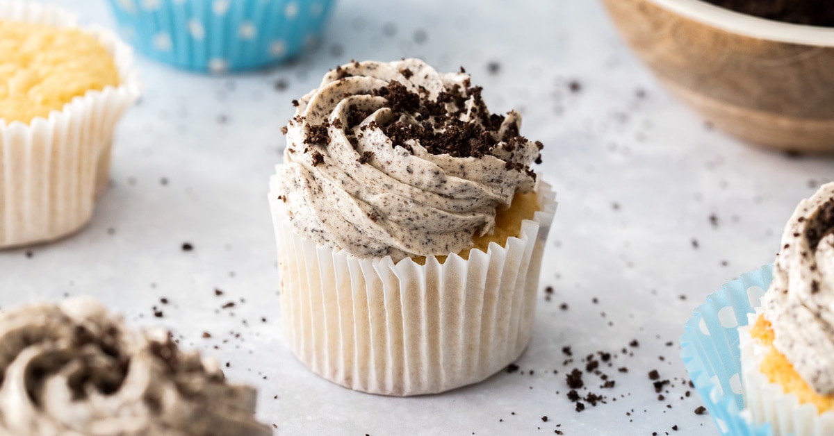 Closeup of a cupcake in a blue polka dot wrapper, topped with oreo buttercream