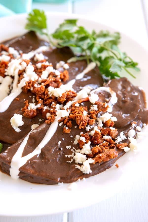 4 frijoles negros enfrijados en un plato espolvoreado con chorizo, queso y crema
