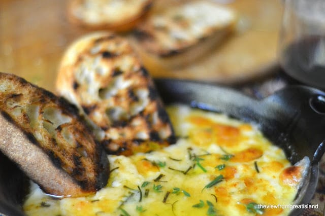 Rebanadas de pan sumergido en un plato de hierro fundido de queso al horno.