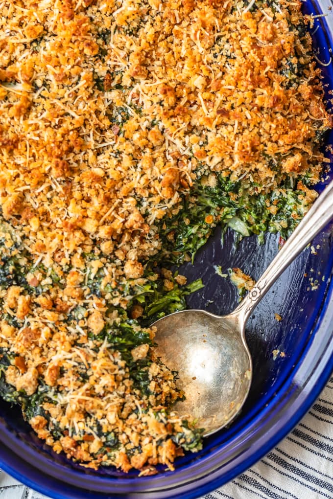Gratinado de espinacas en una cacerola azul con una cuchara para servir