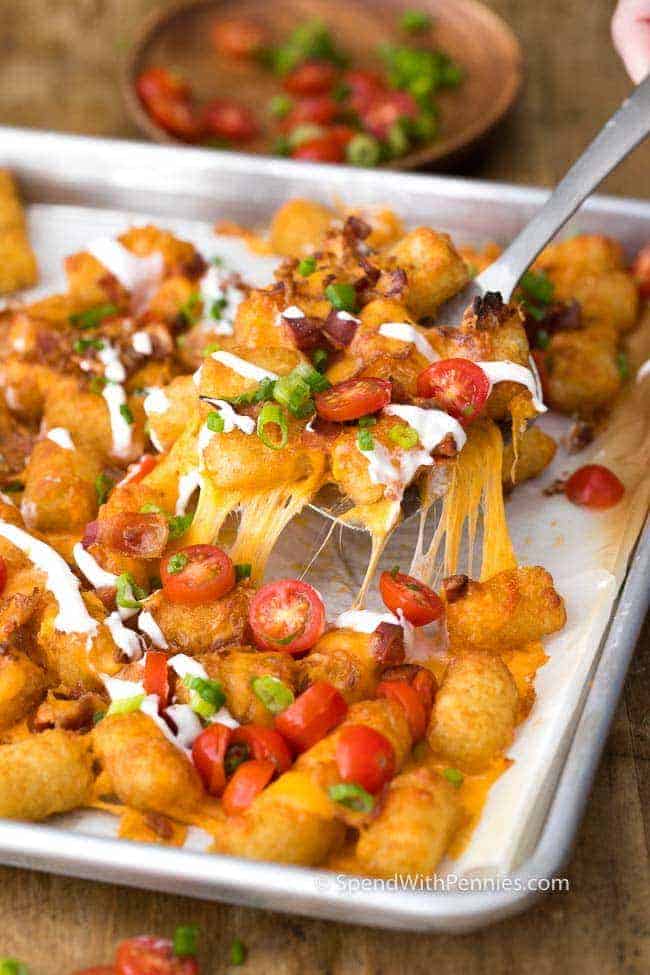 Los Nachos Tater Tot tienen crujientes Tater Tots cubiertos con queso cheddar derretido y tocino. &iexcl;Esta merienda toma solo unos minutos para prepararse y es amada por absolutamente todos!