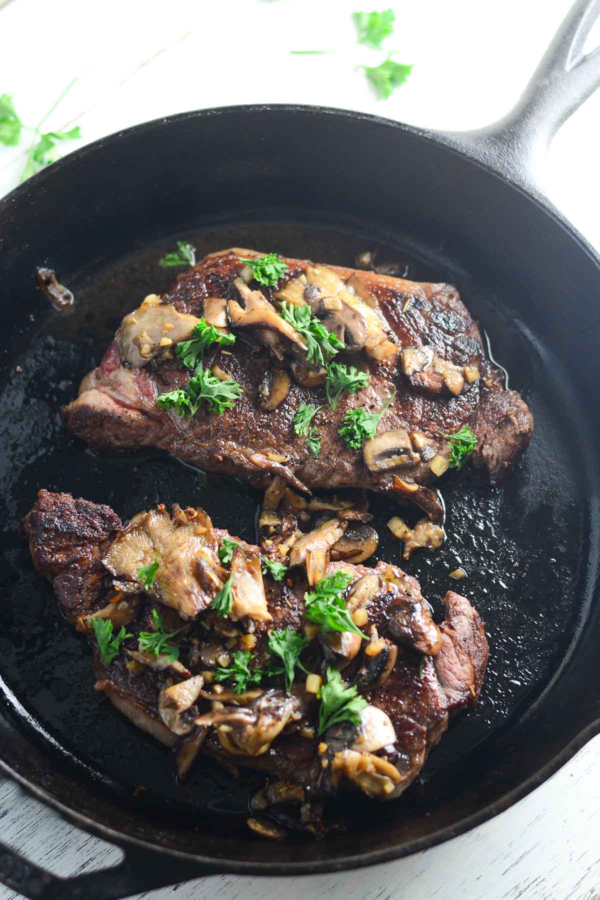 Cast Iron New York Strip with Mushrooms - New York Strip that is sprinkled with sea salt and pepper and seared in a cast iron skillet then finished off in the oven. They are topped with a gourmet blend of mushrooms (baby portabella, shiitake, and oyster) that are sautéed in real butter, freshly minced garlic, and sherry cooking wine.