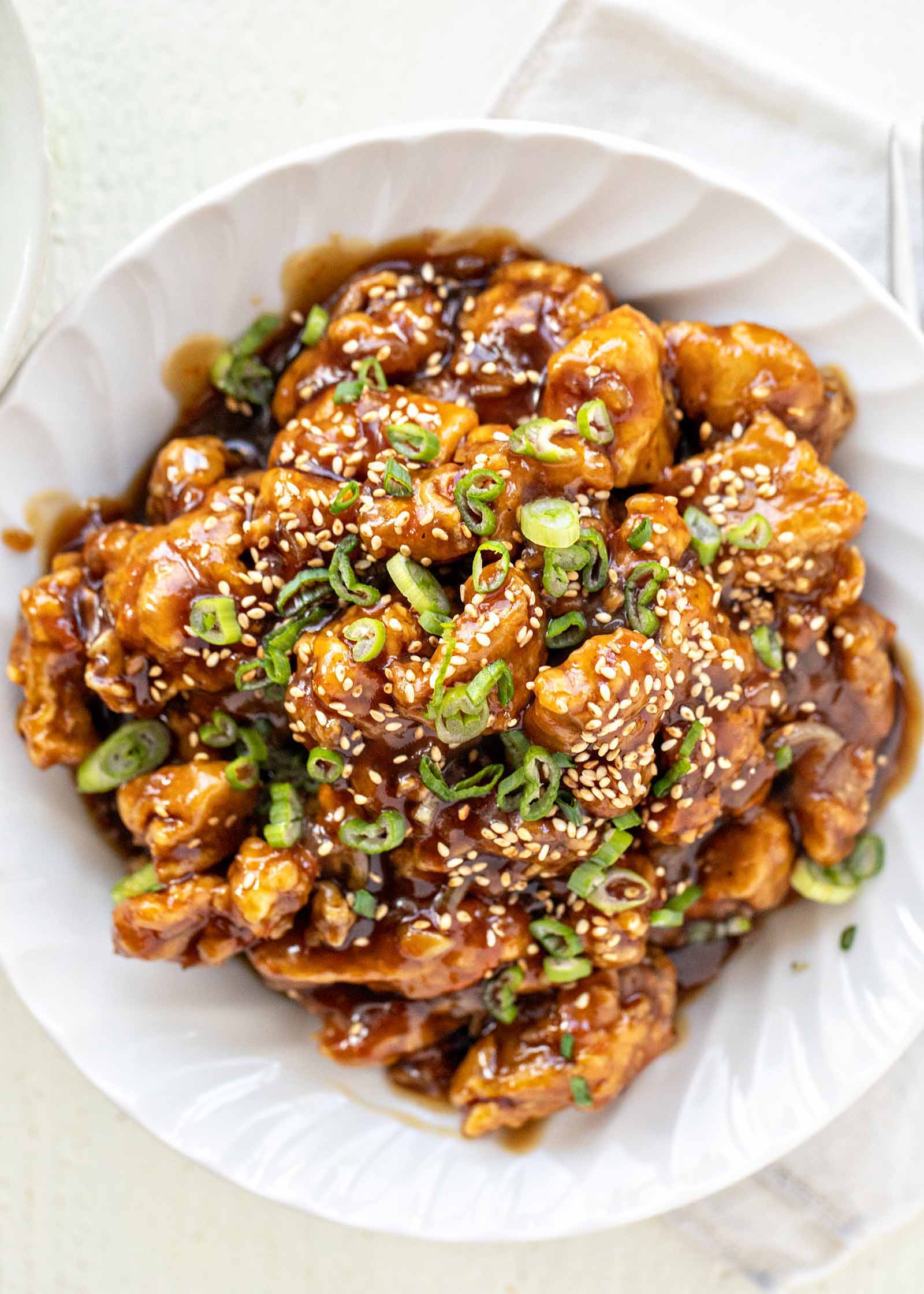 Un bol blanc festonné rempli de poulet à l'orange chinois.