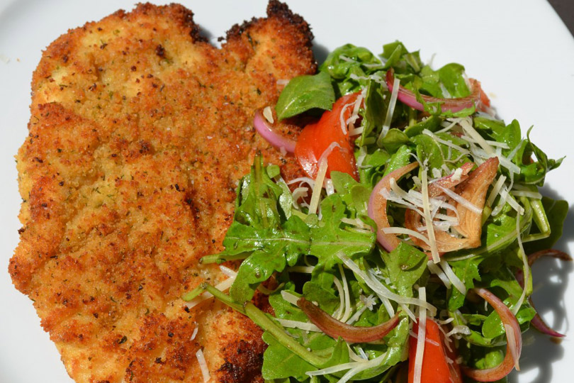 Ensalada de milanesa de pollo sin gluten y rúcula con cebollas rojas marinadas con balsámico