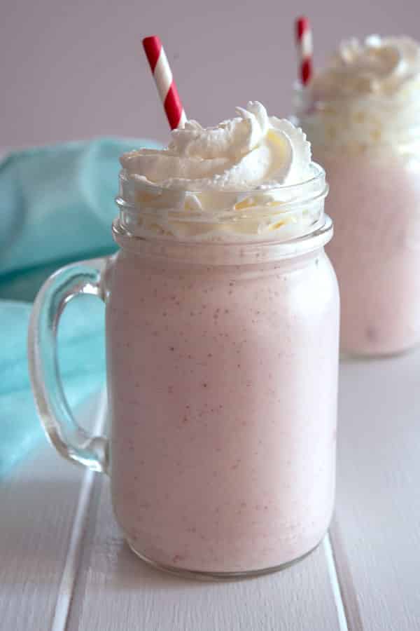 Vaso de cristal lleno de batido de fresa sin helado y crema batida encima