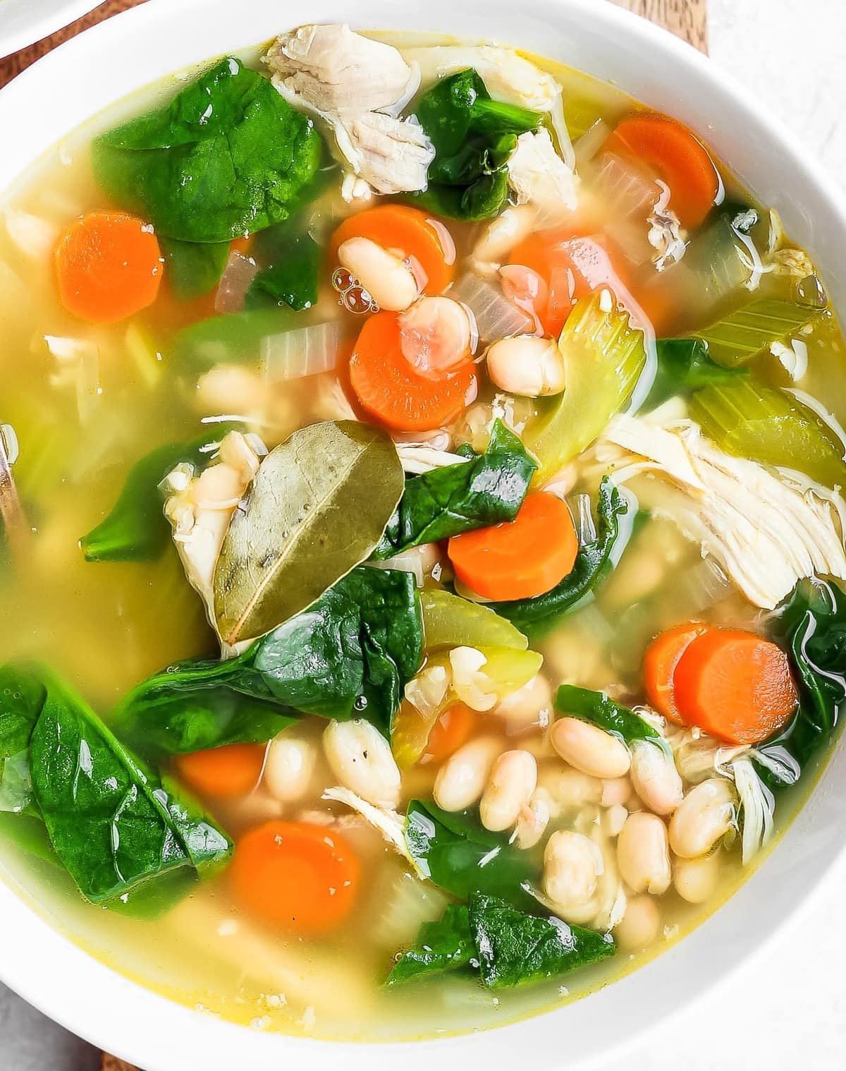taz&oacute;n de sopa lleno de pollo, frijoles, zanahorias y espinacas