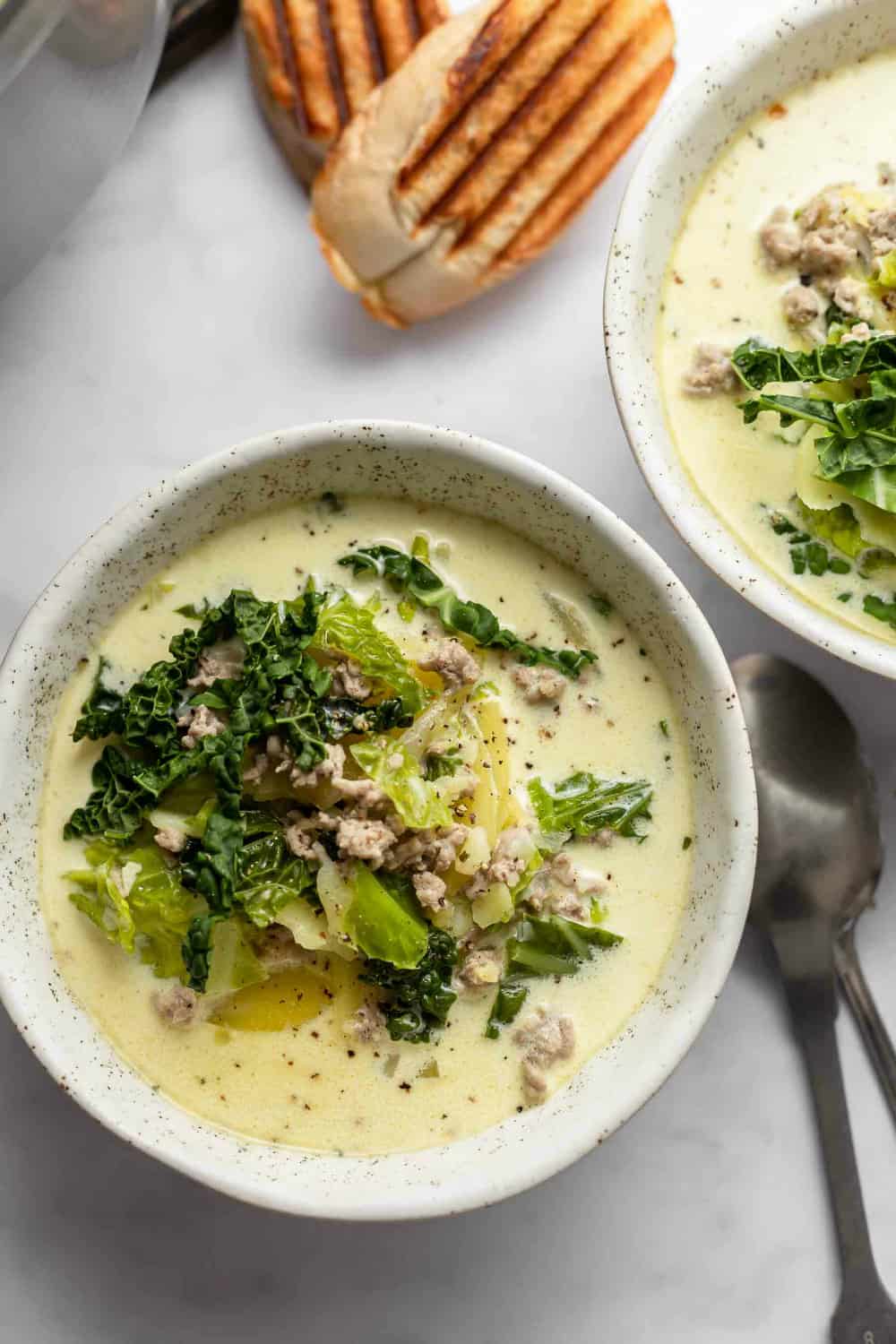 Toscana de zuppa en tazones blancos junto al pan a la parrilla