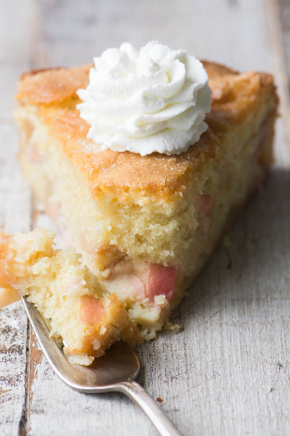 Una rebanada de pastel de duraznos y crema de desayuno con crema batida y tenedor