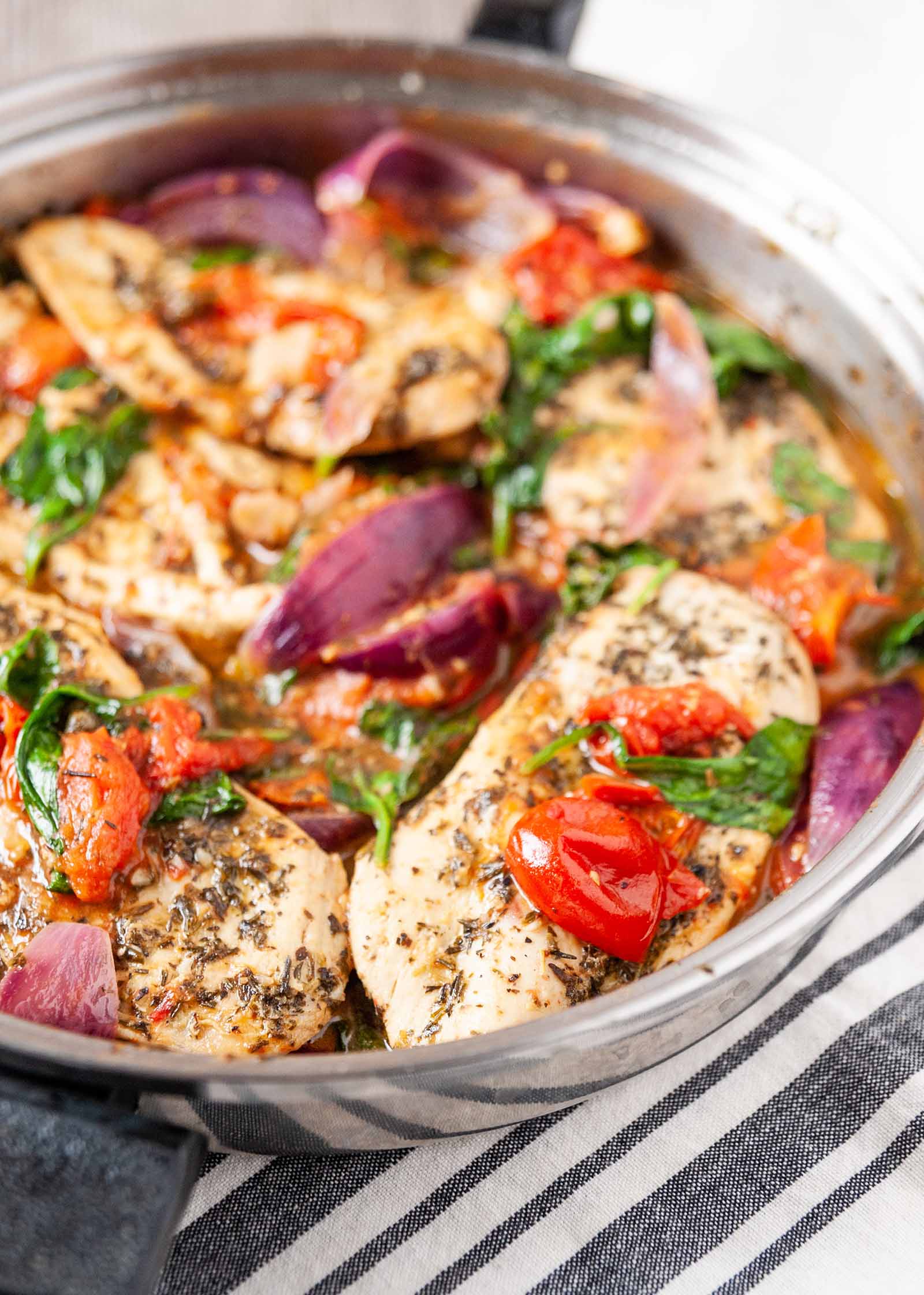 Recette de poulet dans une poêle avec des assaisonnements italiens-gros plan de poulet et de légumes dans une poêle en argent