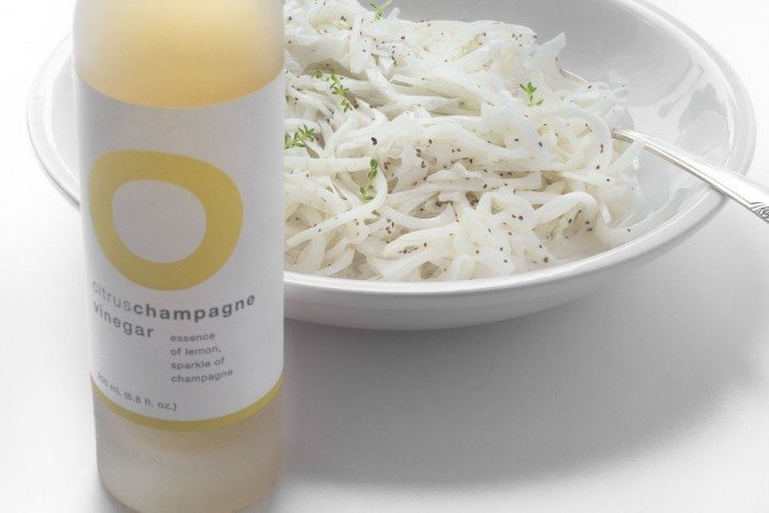 Foto de un plato de ensalada de cebolla dulce vidalia junto a una botella de vinagre de champ&aacute;n c&iacute;tricos.