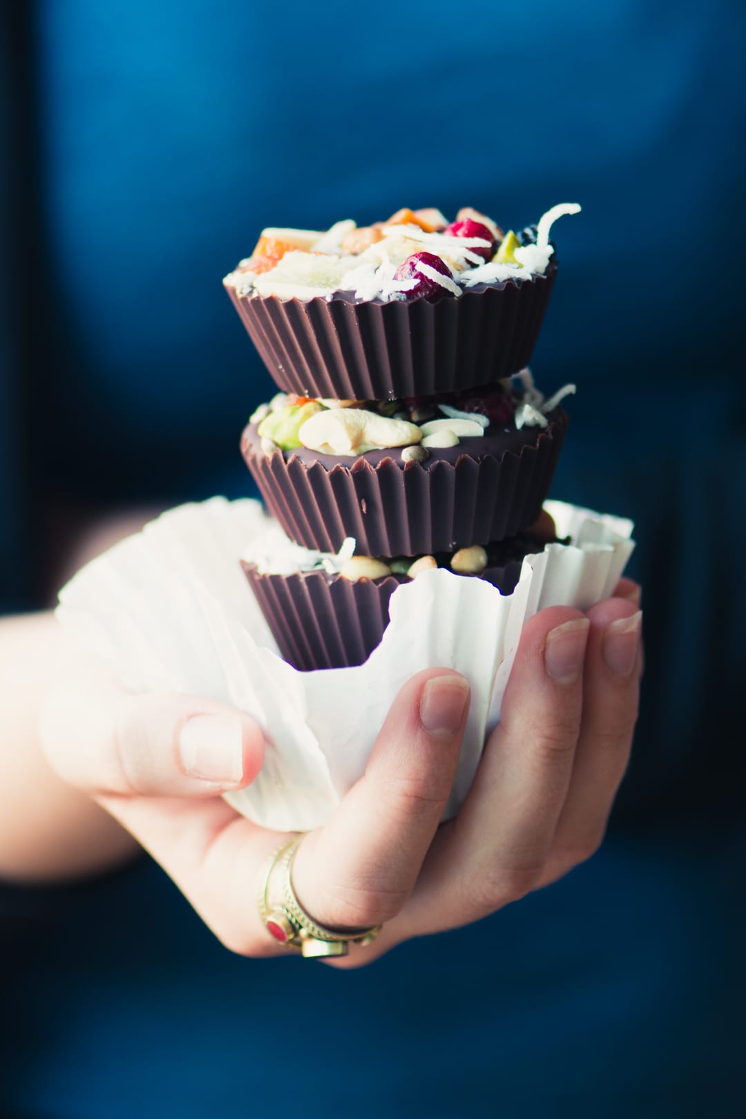 Mano sosteniendo una pila de tazas de mantequilla de almendras con chocolate negro