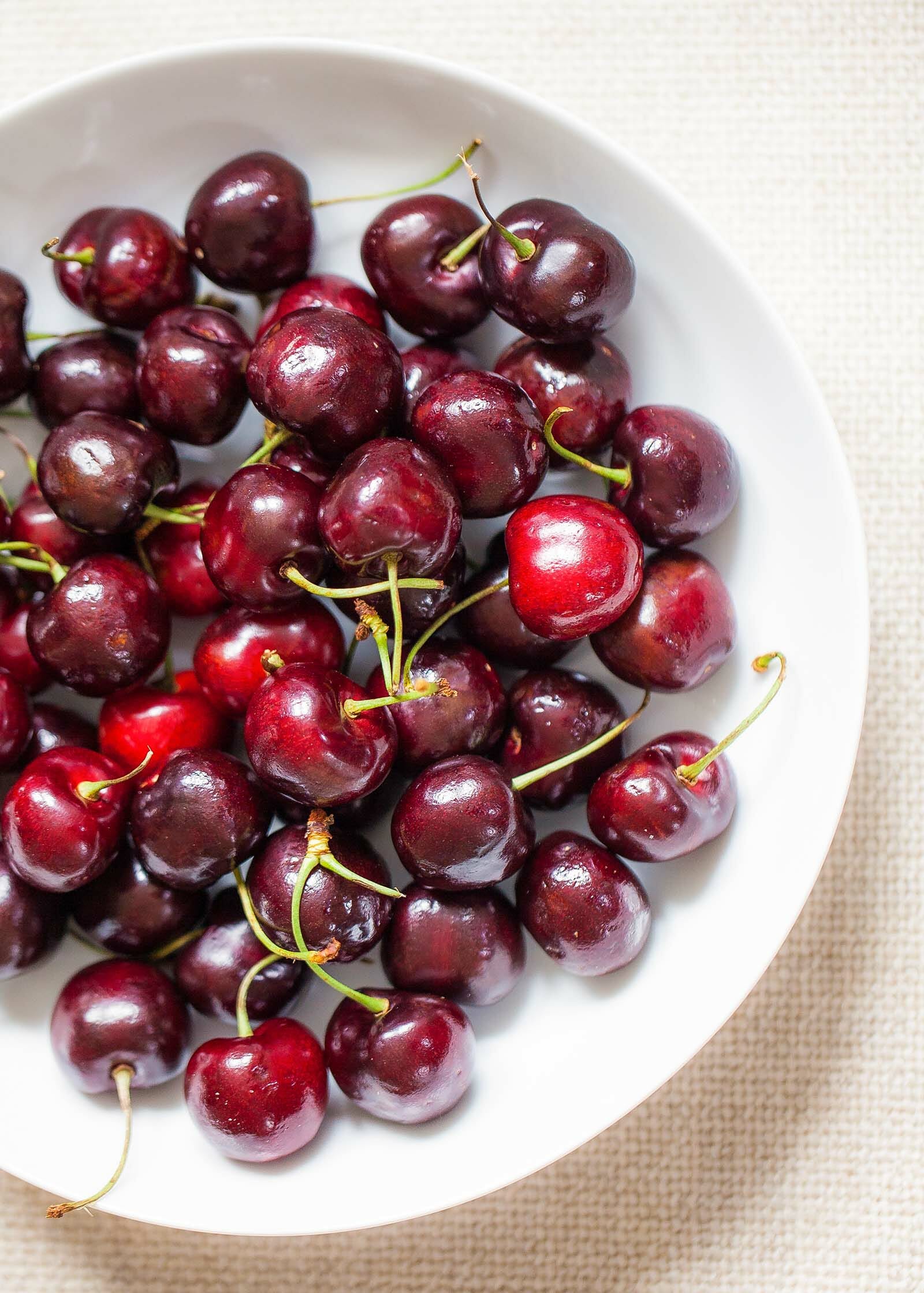 A white bowl filled with red cherries.