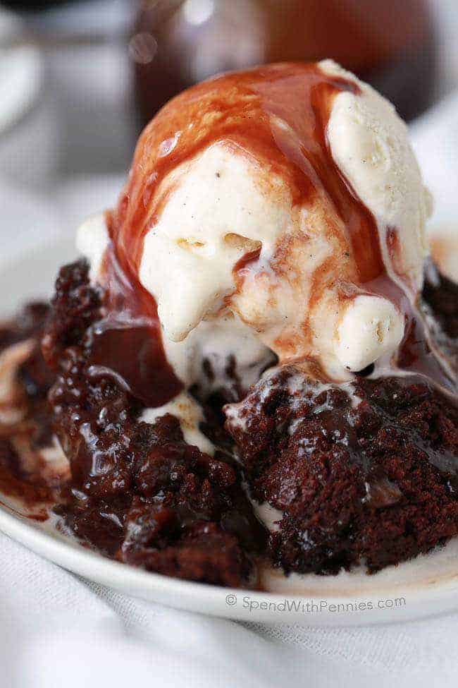 Hot Fudge Slow Cooker Brownie with vanilla ice cream and chocolate sauce on a white plate