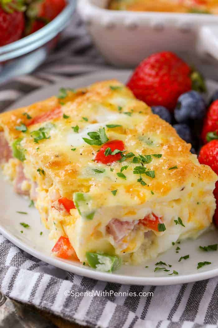 Piece of Denver Egg Casserole on a plate with strawberries and blueberries