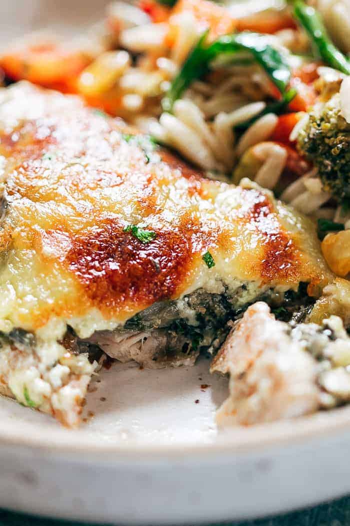 Closeup of a sliced piece of spinach artichoke chicken on a plate with salad