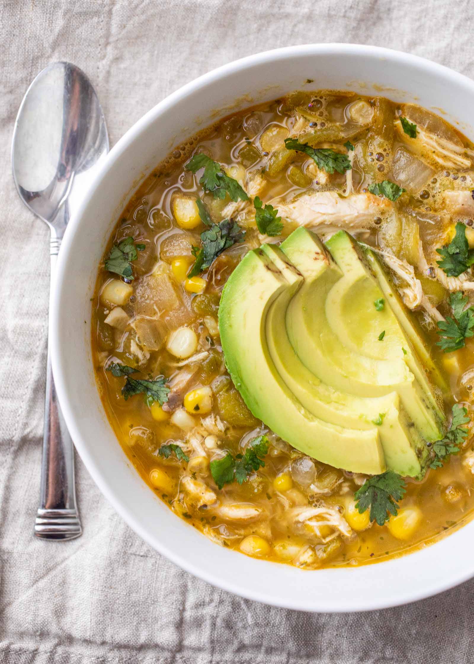 A bowl of Hatch green chili soup with chicken avocado and corn