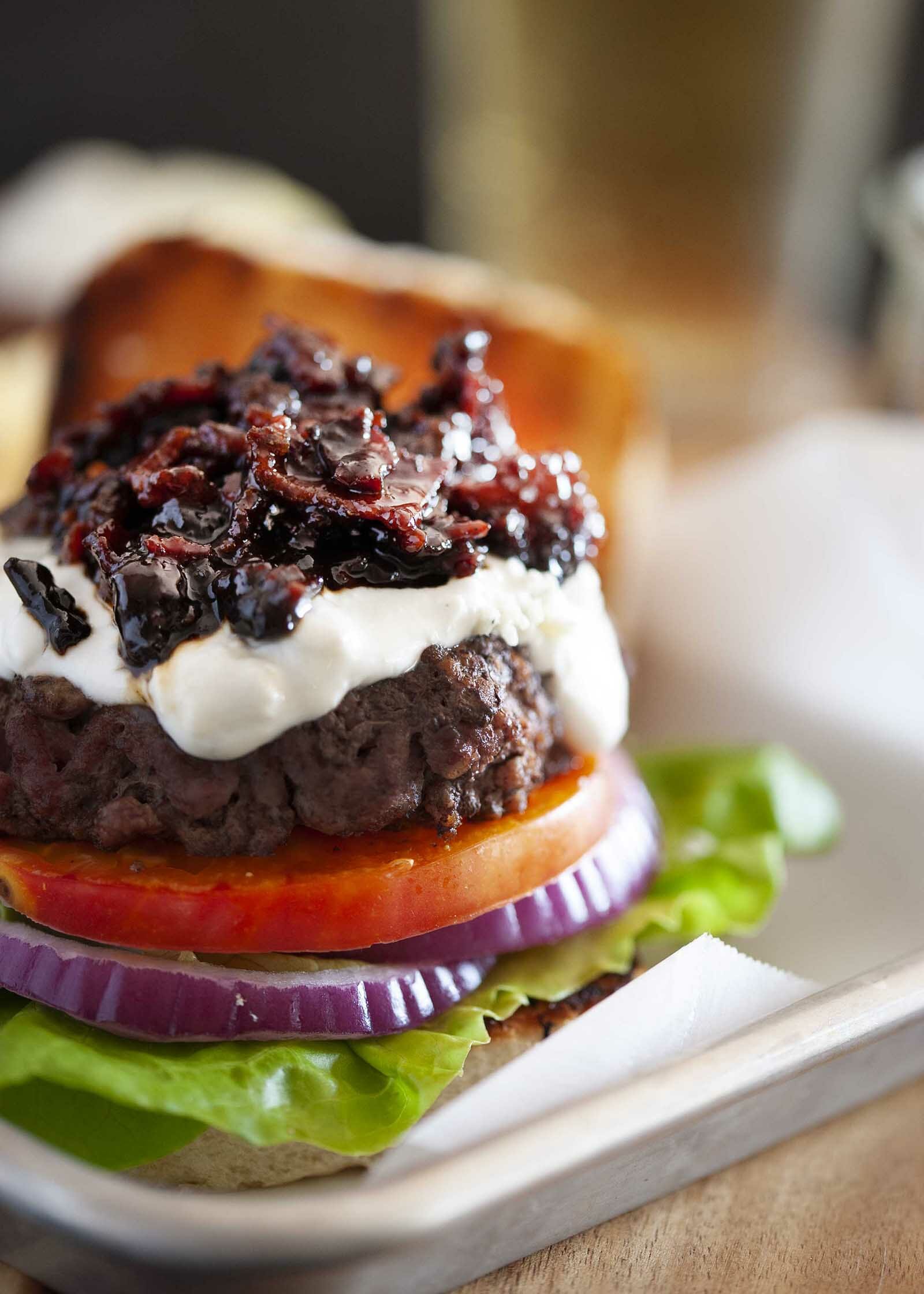 A burger with easy bacon jam on top of sauce, tomato, red onion and lettuce.