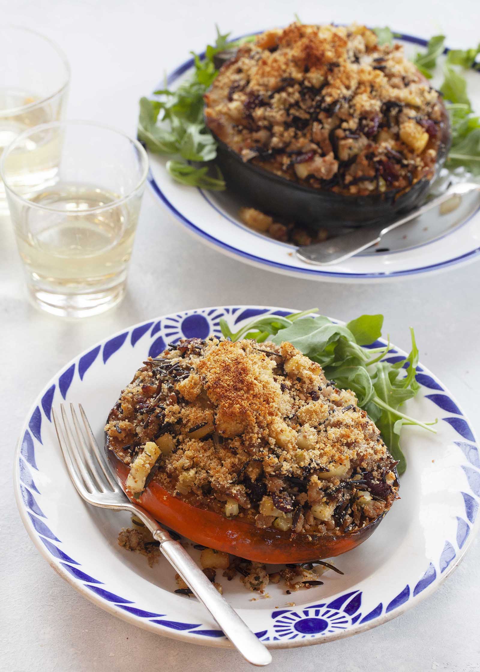 Easy Stuffed Squash: Acorn Squash on a plate stuffed with turkey sausage and rice. A glass is nearby filled with white wine.