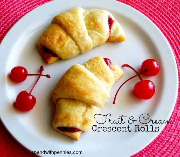 fruit and cream crescent rolls with cherries on the side, on a white plate