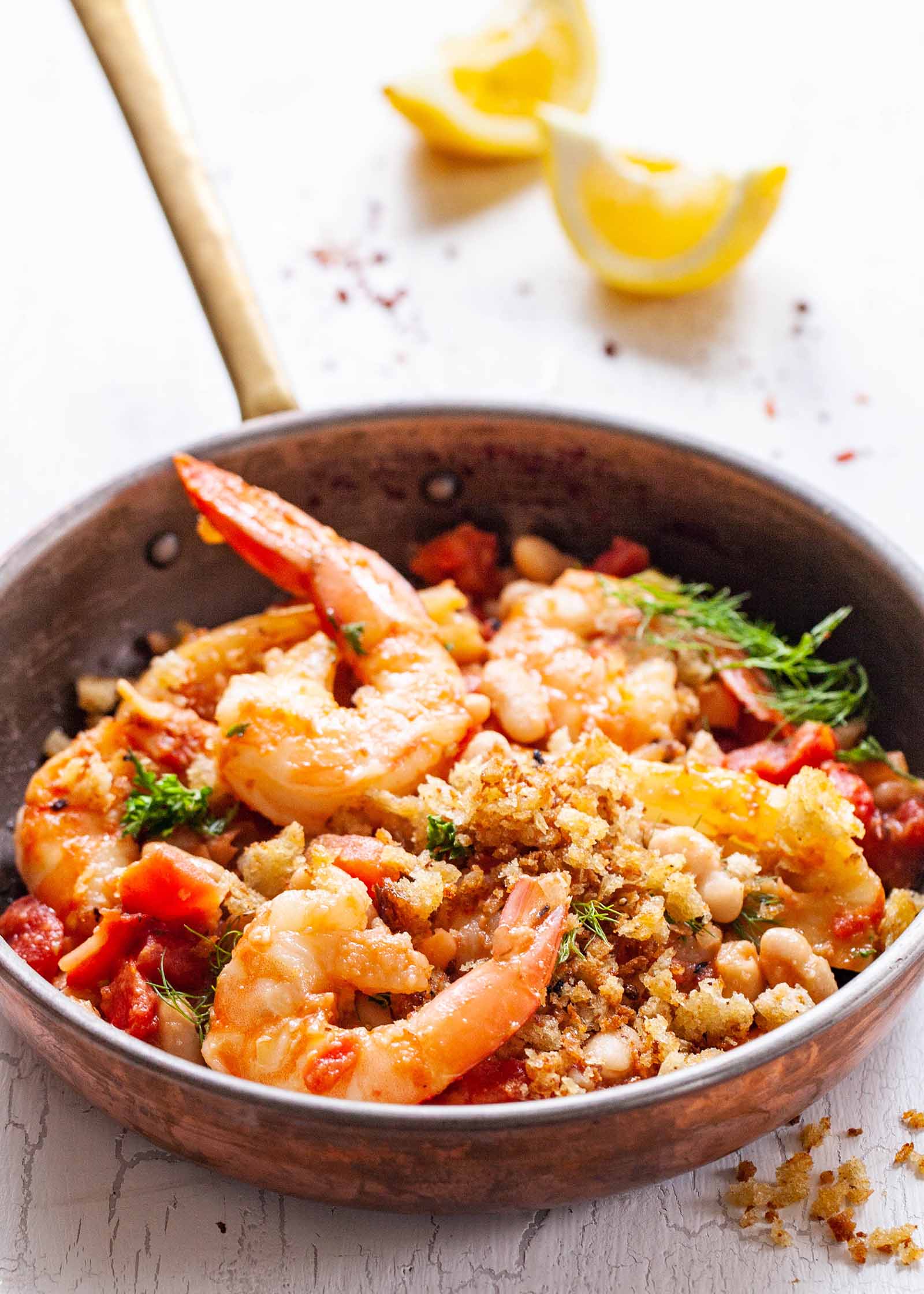 Weeknight Shrimp Dinner - shrimp, breadcrumbs, vegetables, tomatoes and beans in skillet with lemon wedges