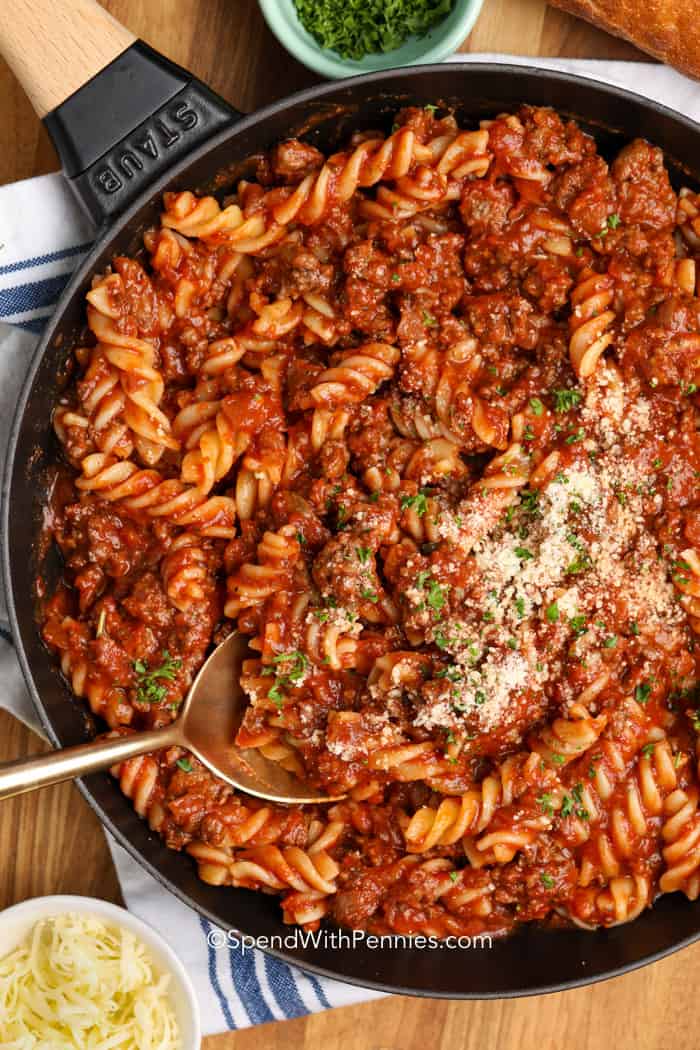 Fusilli with meat sauce in a pan garnished with parsley.