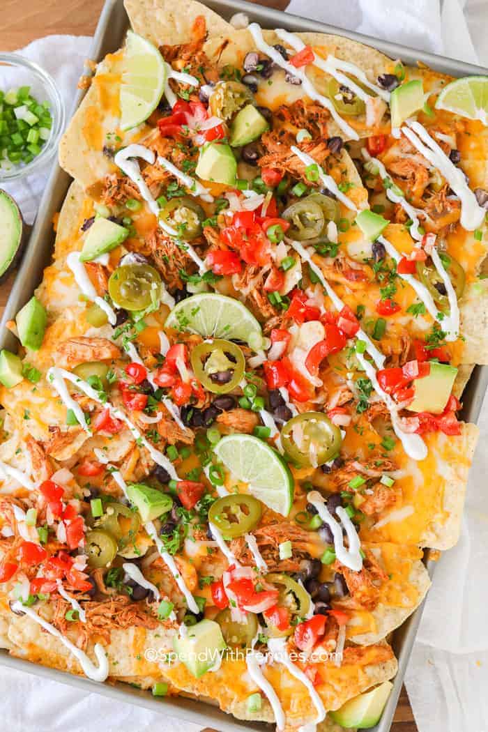Loaded Nachos on a baking sheet with sour cream drizzled on