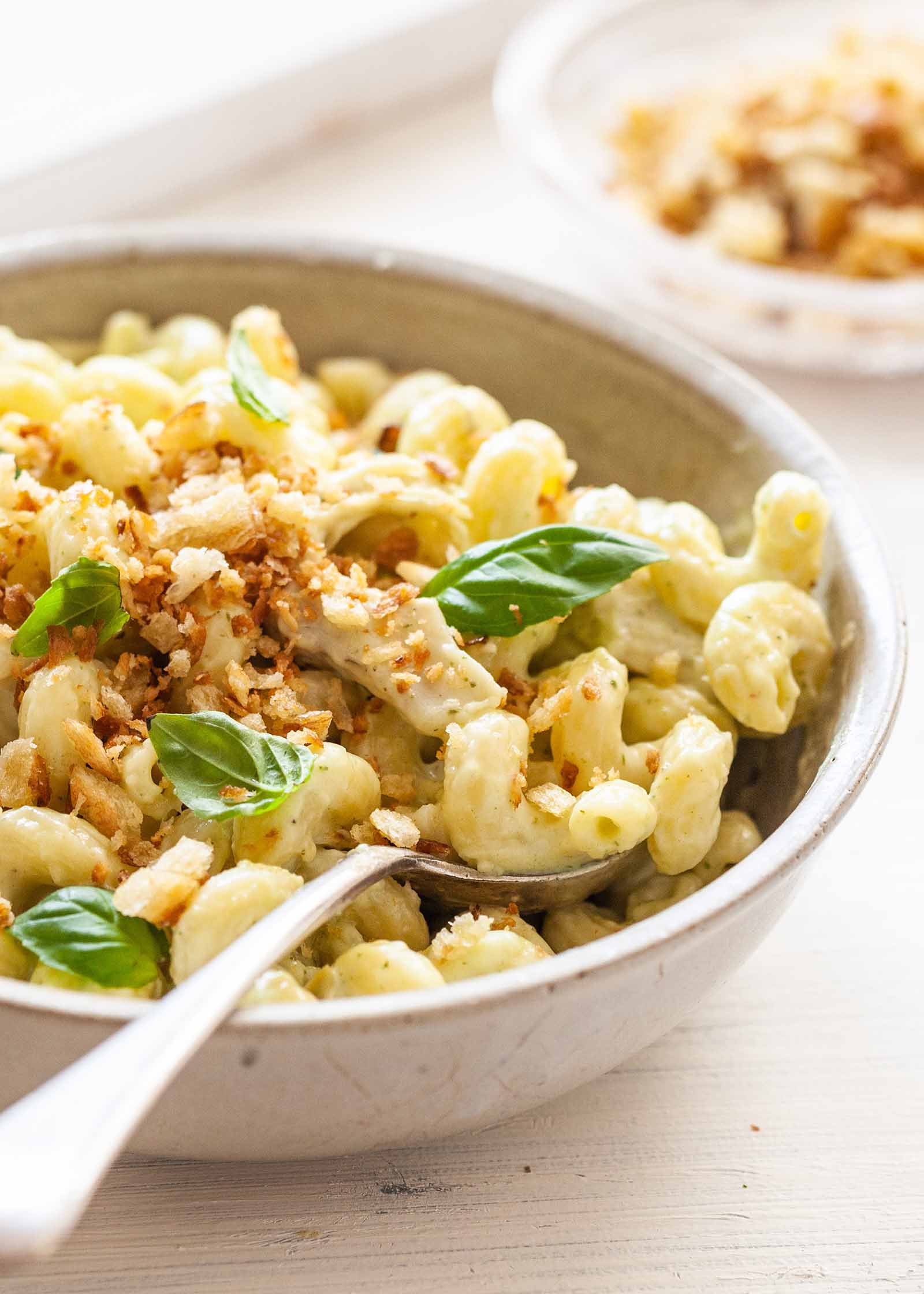 Mac and Cheese Add-Ins - mac and cheese in bowl with basil leaves and breadcrumbs on top