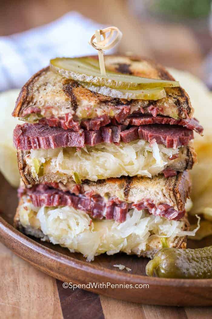 Reuben Sandwiches on a plate with sauerkraut and pickle slices