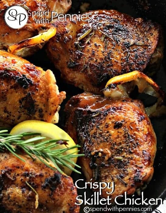 aCrispy Skillet Chicken with crispy skin, roasted lemons and rosemary garnish in a skillet