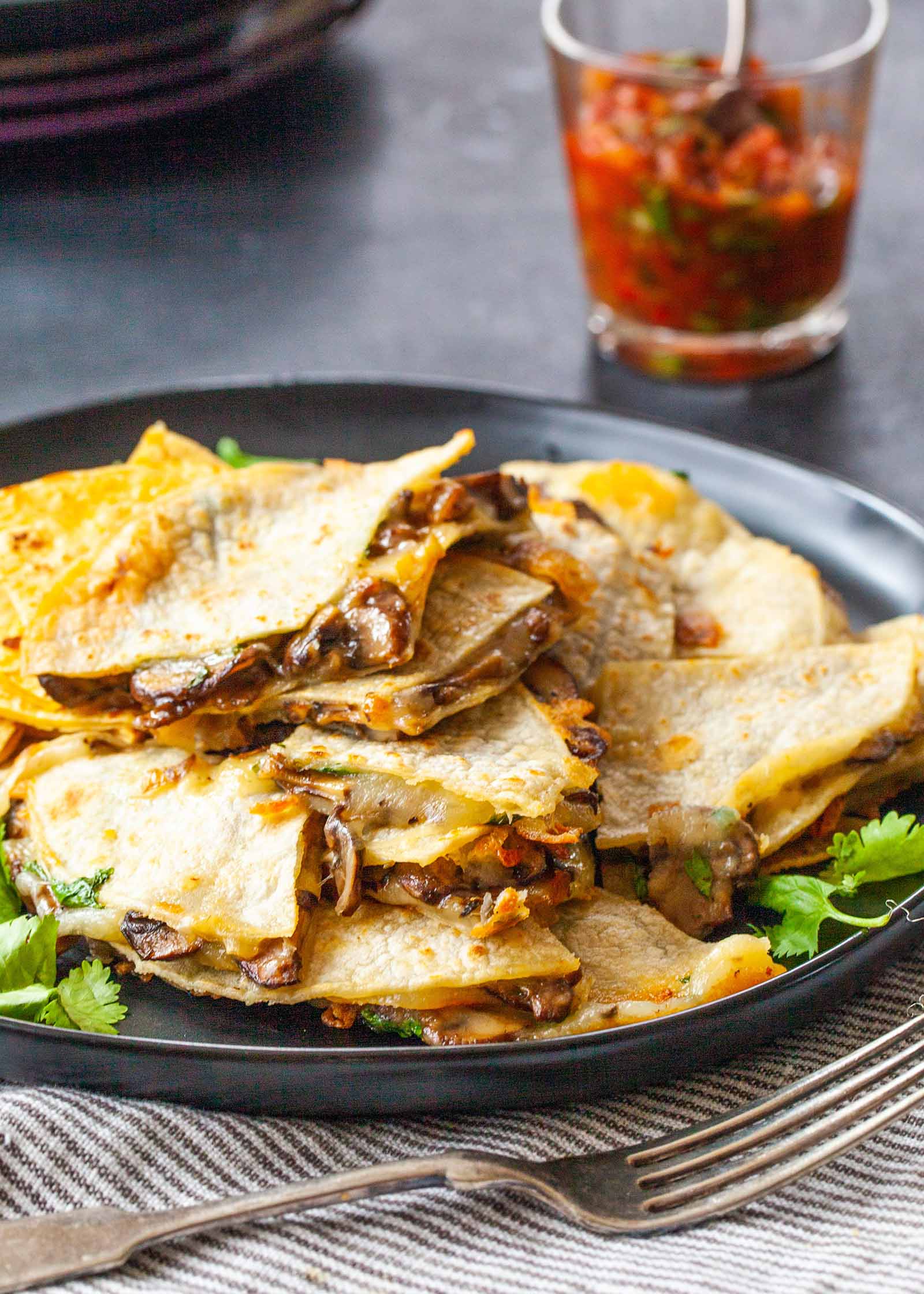How to Make a Cheese Quesadilla with Mushrooms - dark plate with stack of mushroom and cheese quesadillas and a jar of salsa in the background