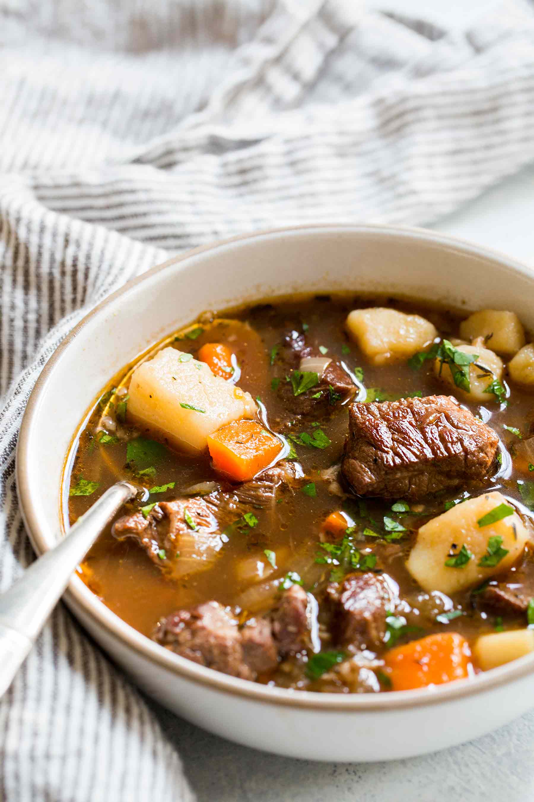 Beef stew recipe made with chuck roast, carrots, and potatoes served in a bowl with a spoon