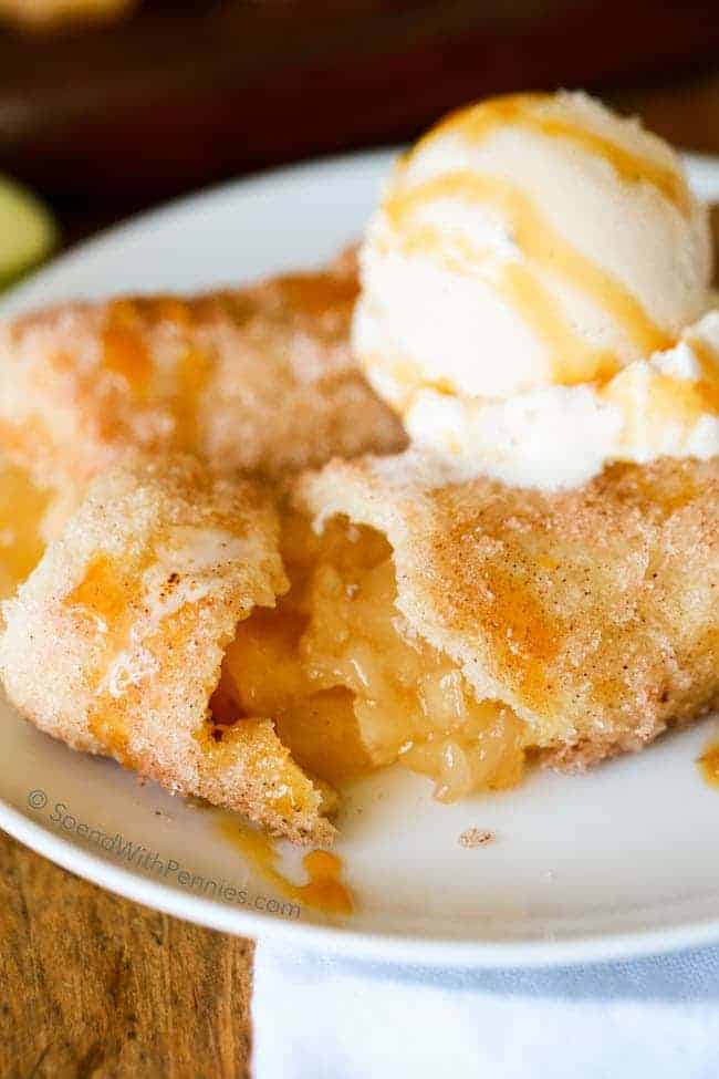 apple pie rollups with ice cream and caramel on a white plate