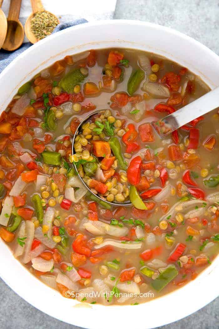 Overhead shot of Lentil Soup in a white pot with a silver ladle