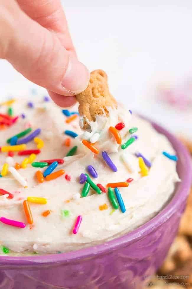 Dippin a teddy graham in Dunkaroo Dip in a purple bowl