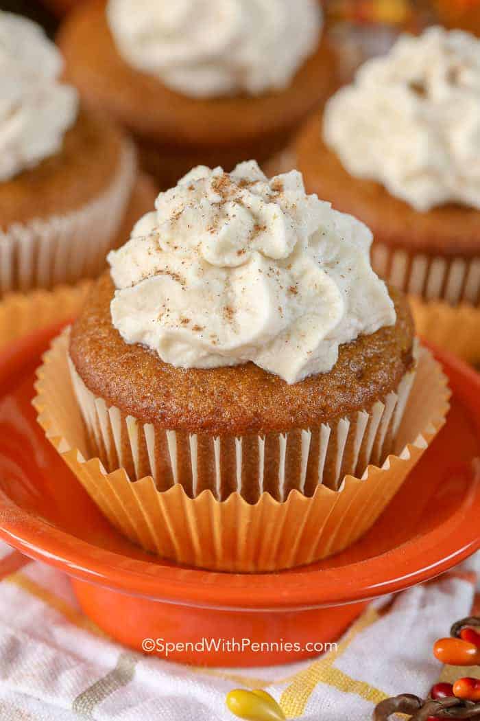 Pumpkin Cupcake with wrapper still on it on an orange dish