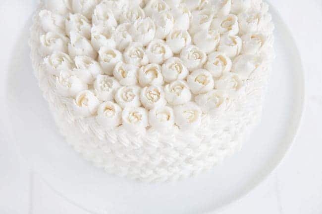 ¡Pastel cubierto de crema blanca con rosas rusas en la parte superior!