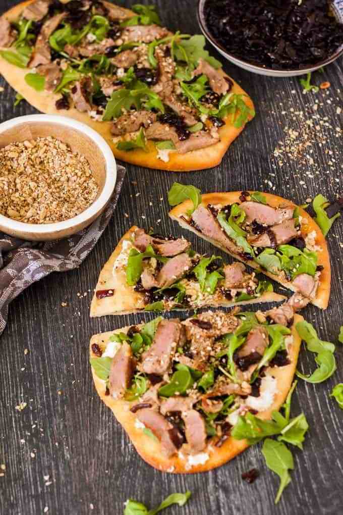 Questa focaccia di agnello con condimento di cipolla caramellata, Dukkah fatta in casa, formaggio feta e rucola è un pranzo o una cena facile e sorprendente.