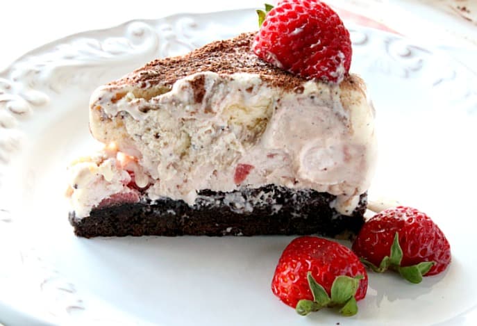 Una singola fetta di torta gelato napoletana su un piatto bianco con un contorno di fragole.