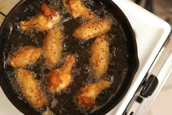 Friggere le ali di pollo in una padella d'olio.