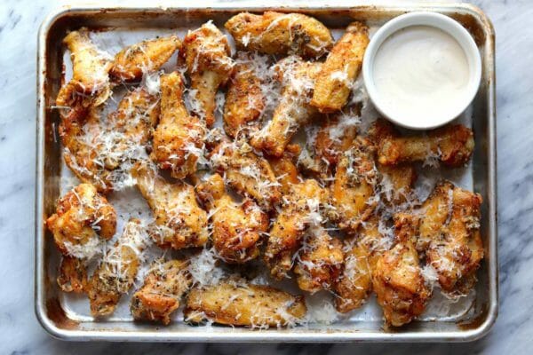 Ali di pollo fritto con parmigiano appena grattugiato su una grande teglia