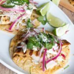 Tacos di pesce alla griglia marinati nella birra, questi classici tacos sono conditi con cavolo grattugiato, ravanelli, cipolle rosse sottaceto, fette di jalapeño e formaggio cojita.