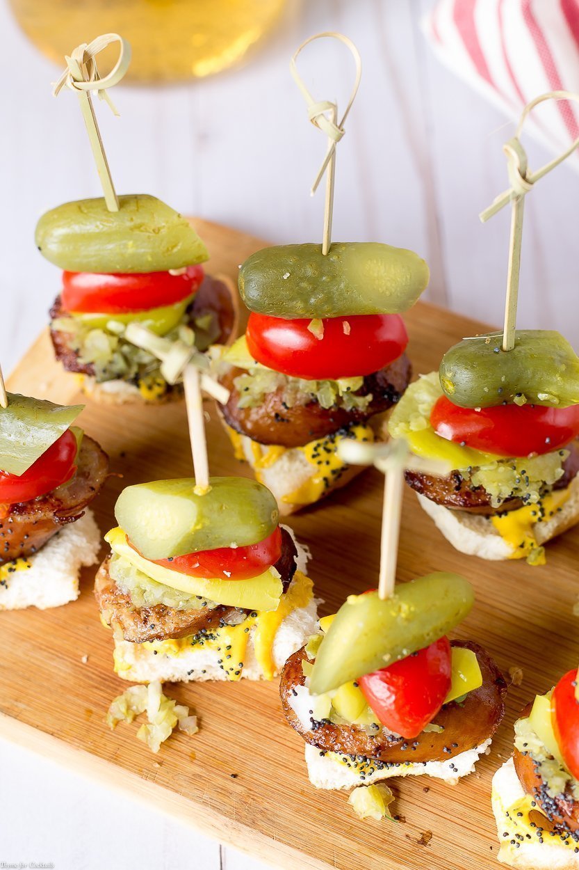 toast, spessa fetta di salsiccia affumicata, condimento dolce, cipolla bianca, senape gialla, lancia sottaceto, semi di sesamo, tutto in un boccone su uno spiedino, sparato dall'alto