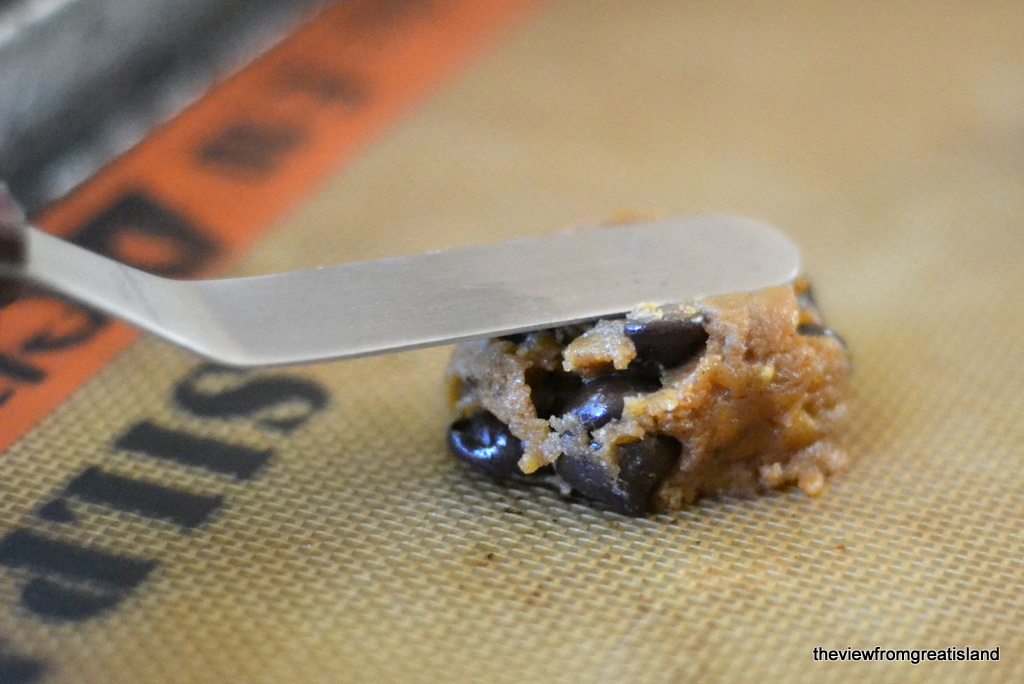 Foto di farina di mandorle senza farina con gocce di cioccolato Pasta biscotto schiacciata con una spatola su una teglia.