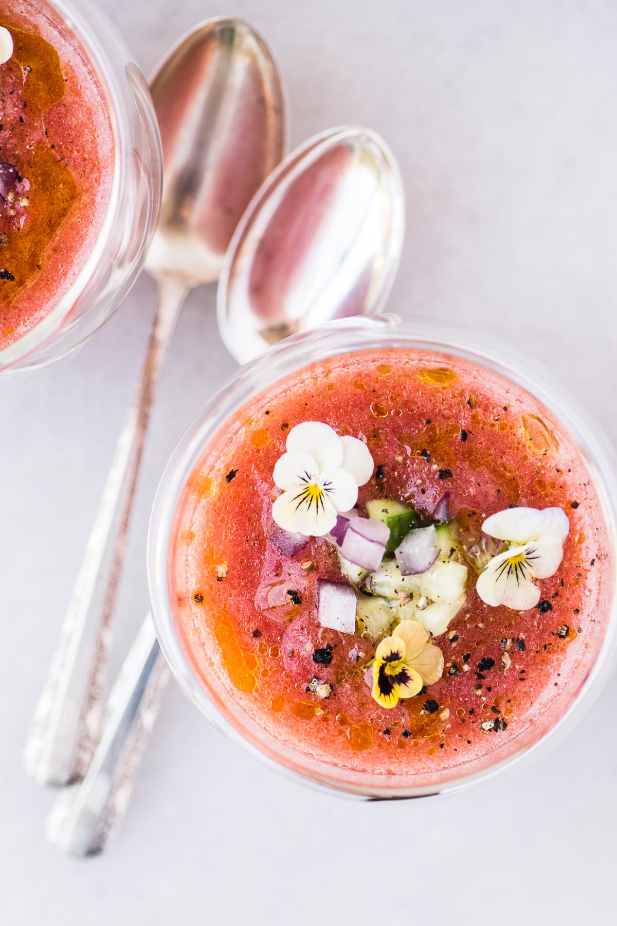 Gazpacho di pomodoro fresco in piccoli bicchieri ricoperti di verdure fresche e fiori commestibili